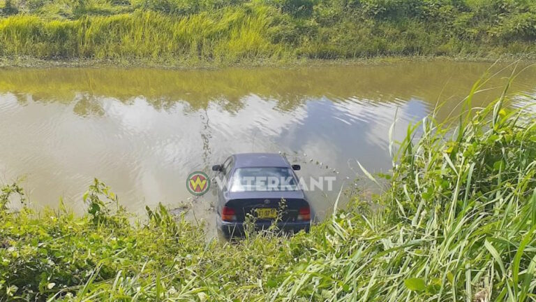 Auto eindigt in het water langs de weg in Suriname
