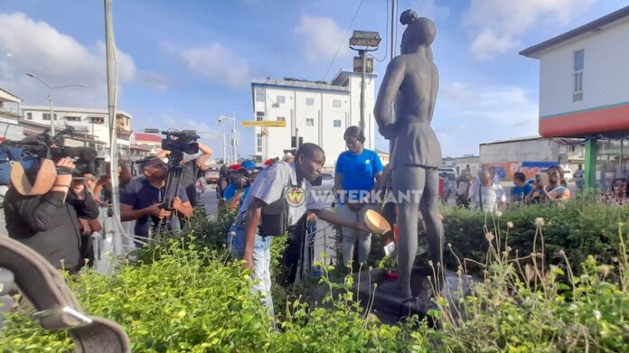 Handjevol mensen bij protest tegen excuses slavernijverleden bij beeld Kwakoe